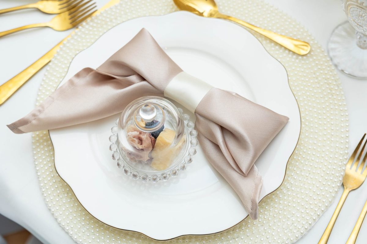 Handmade pearl chargers with gold flatware and satin napkins at baby shower