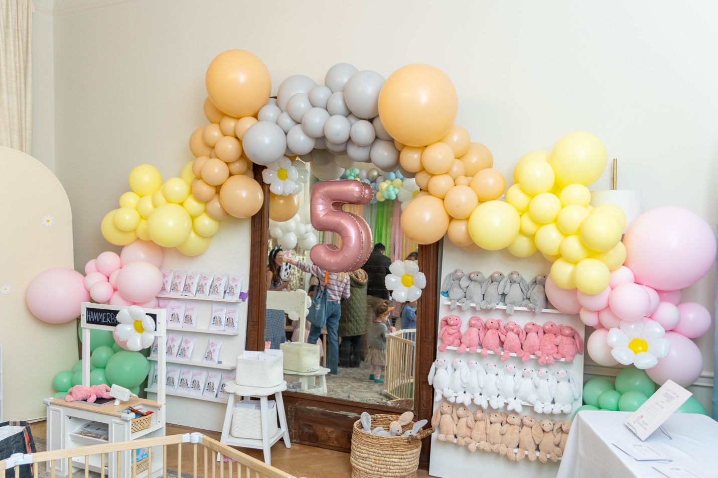 Balloon garland in peach, butter yellow, baby pink, and sage with a rose gold "5" foil balloon and oversized daisy balloons