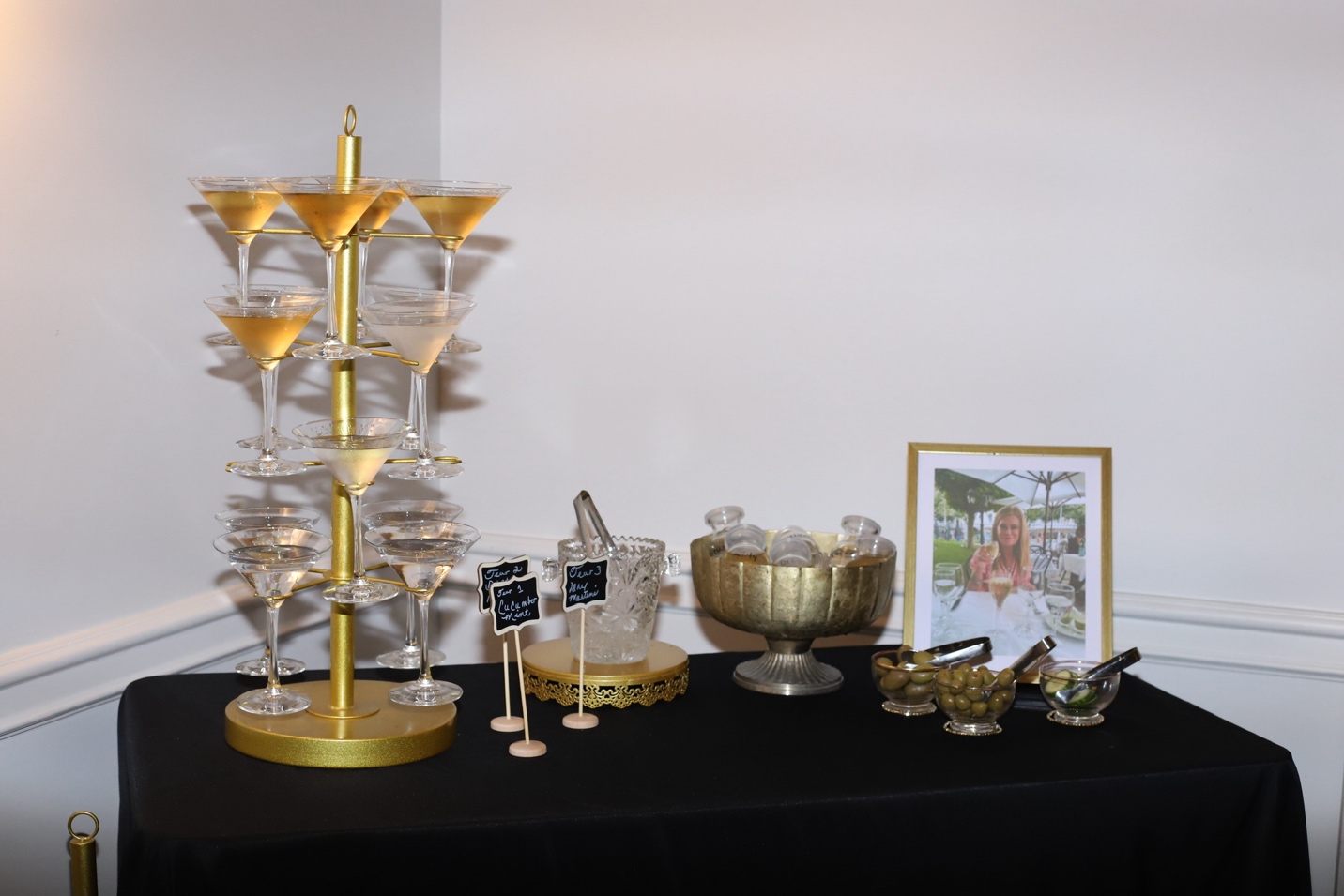 The gold martini tower with tiered glasses, crystal ice bucket, hammered gold punch bowl, chalkboard signs, and a framed photo